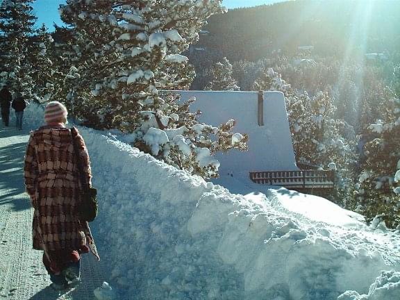 A woman climbs up a snowy mountain in a long pink winter coat while practicing resilience