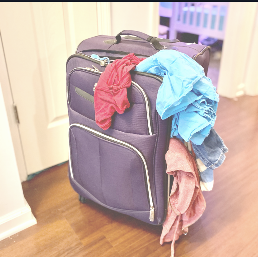 A purple suitcase is stuffed full of baggage that is spilling out on all sides